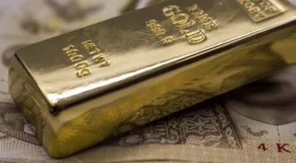 gold bullion bar resting on dollar