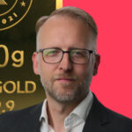 Frank Watson headshot in front of gold bullion background.